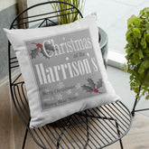 A personalised white, grey and red Christmas cushion with a text based design and holly leaf illustrations